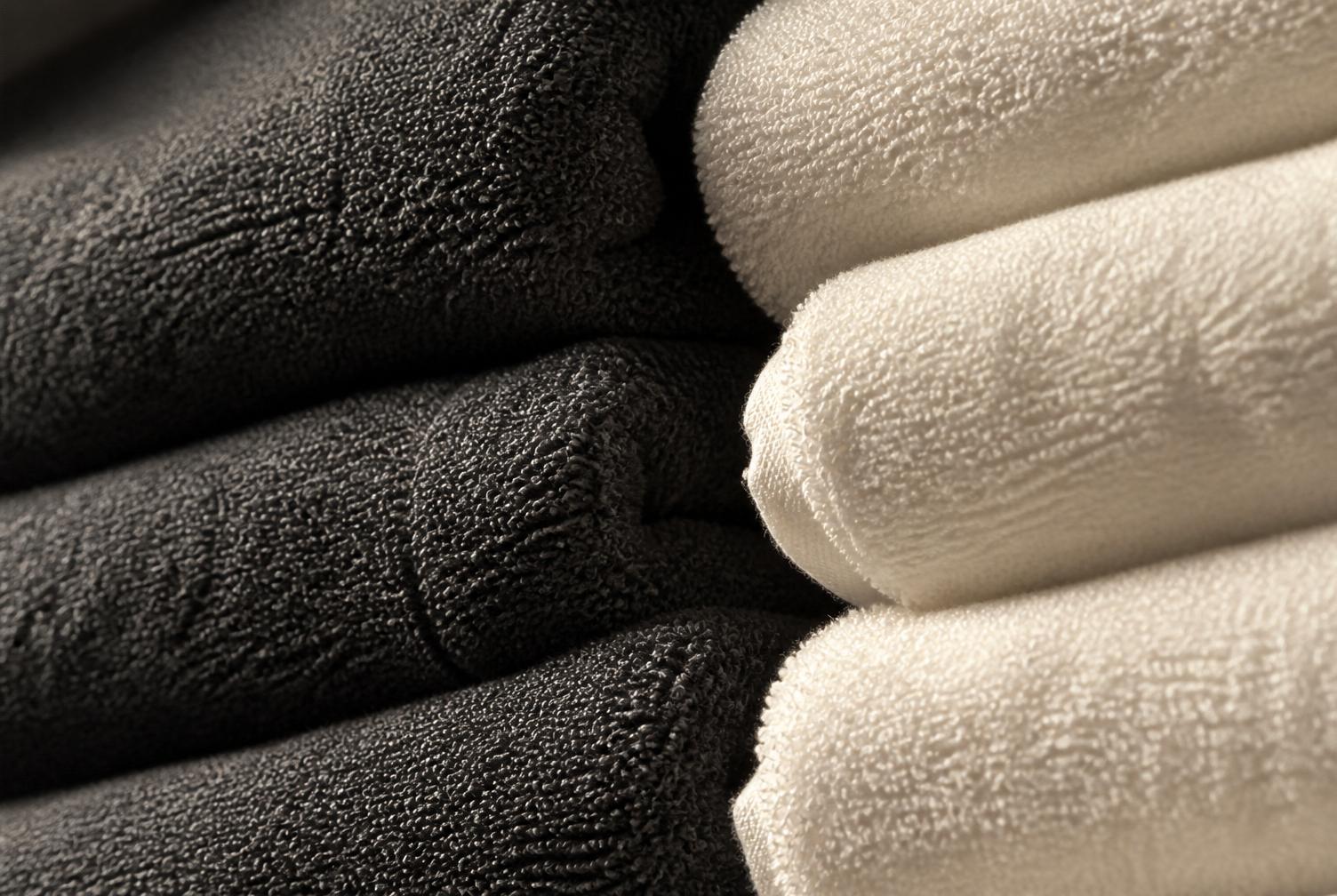 Close-up of folded charcoal and white salon towels showing terry texture.